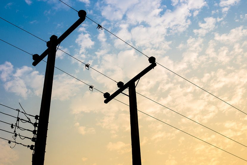 Two silhoutted telephone poles with a dramatic blue and orange cloudy sky in the background.